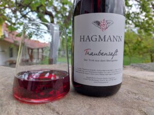 roter Traubensaft im Glas und Trauensaft-Flasche mit neuem Etikett