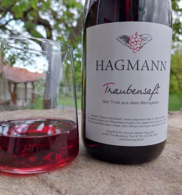 roter Traubensaft im Glas und Trauensaft-Flasche mit neuem Etikett